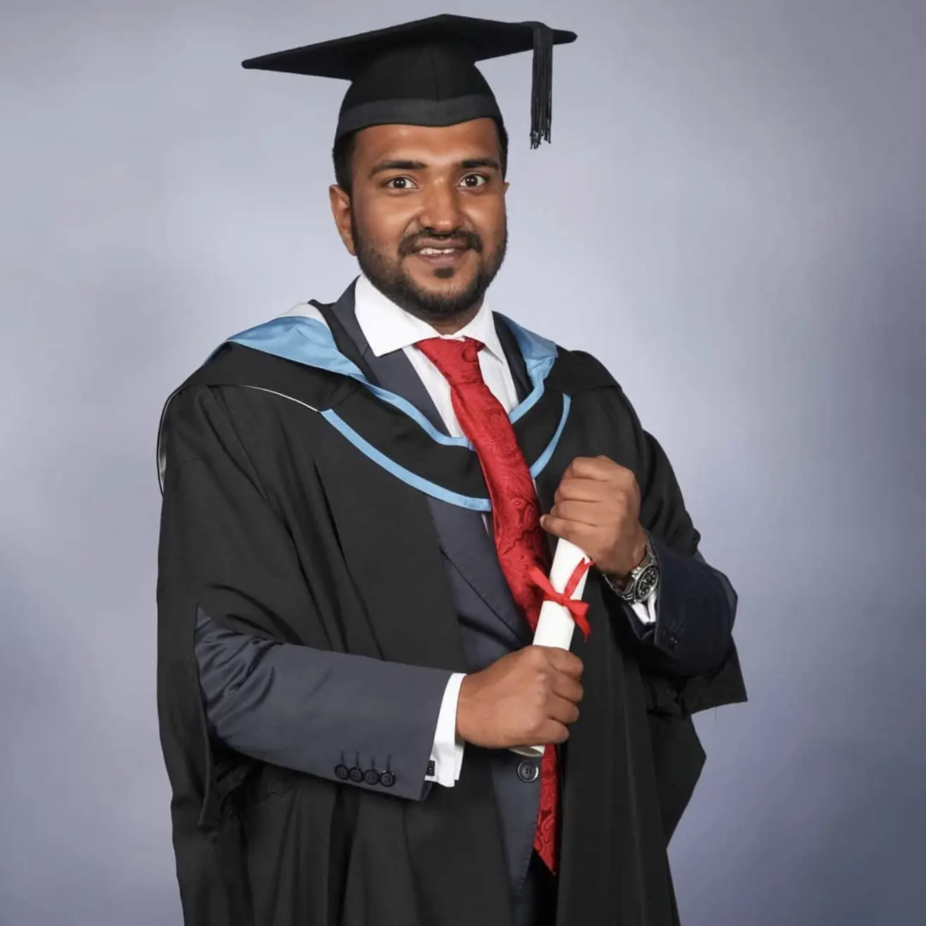Cyrus in academic dress holding a graduation scroll