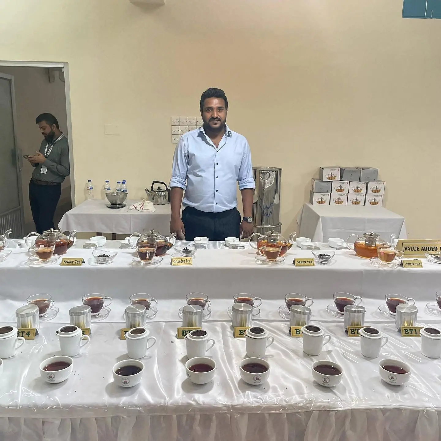 Cyrus beside a tea tasting display with prepared samples